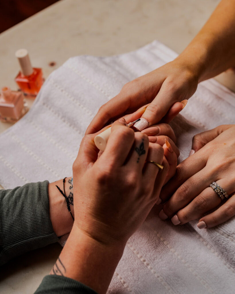 A woman at The Village community event getting her nails done, showcasing connection and social club.