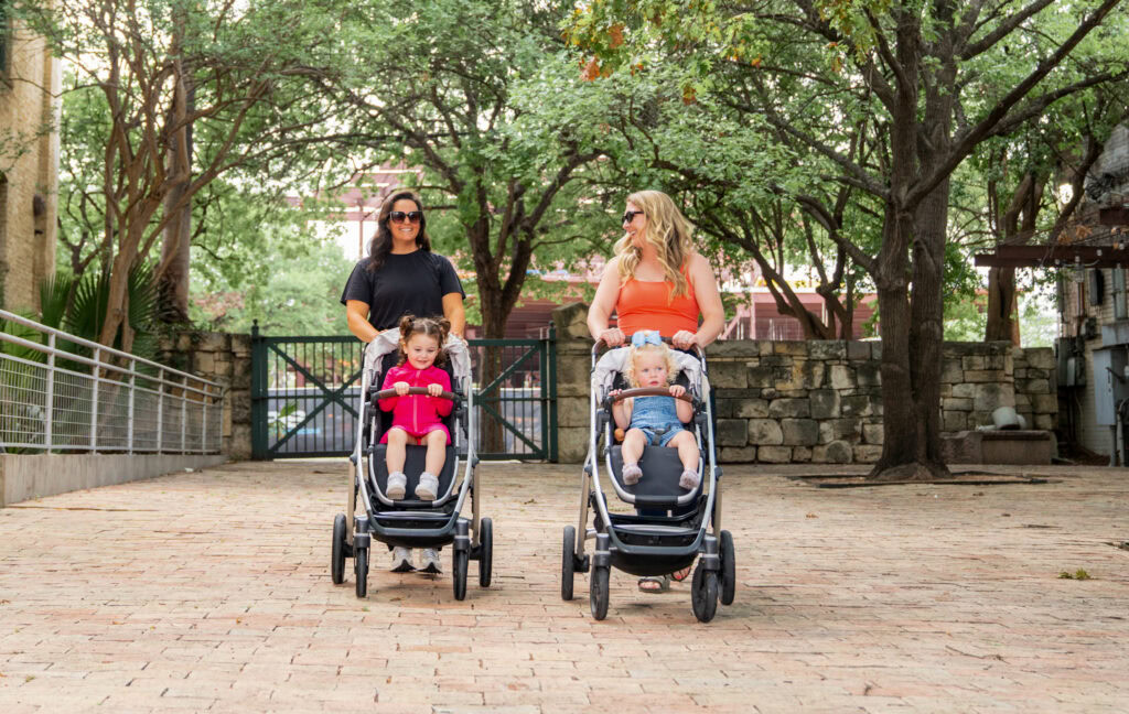 Two women with children in strollers enjoying The Village community in San Antonio.