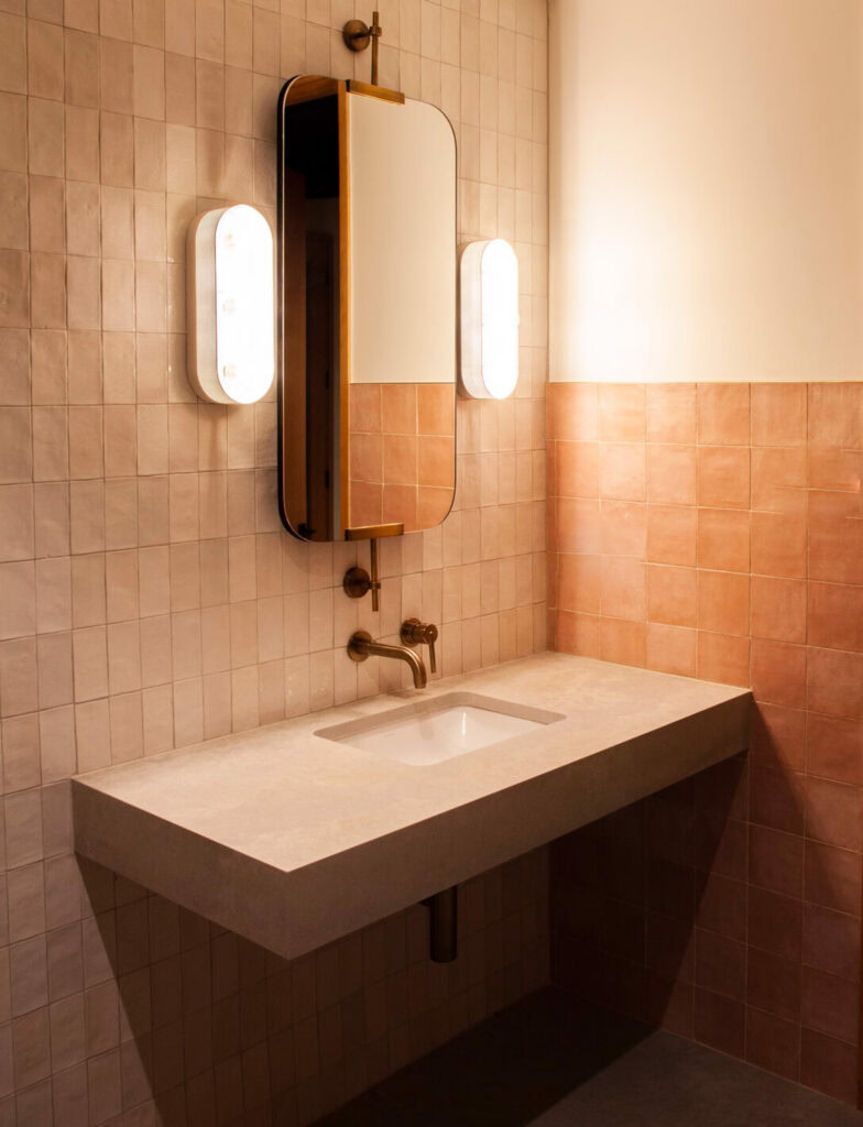 A bathroom with a modern sink and mirror at The Village social club in San Antonio.