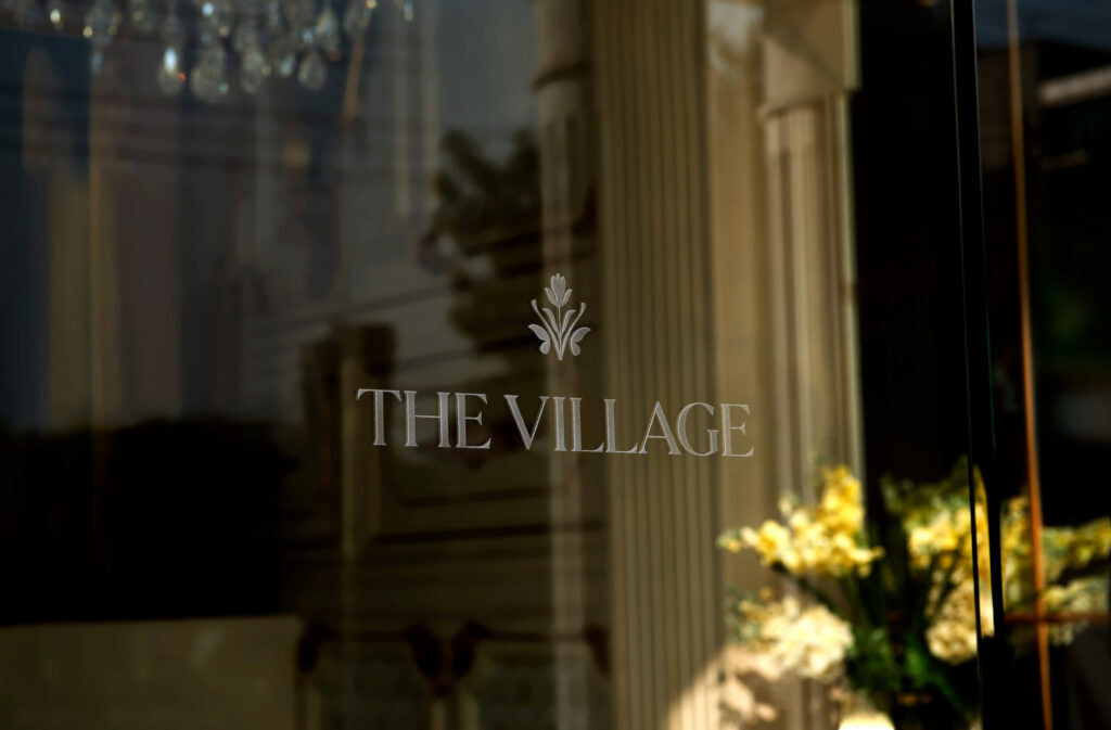 The Village San Antonio community social club entrance with flowers and logo.