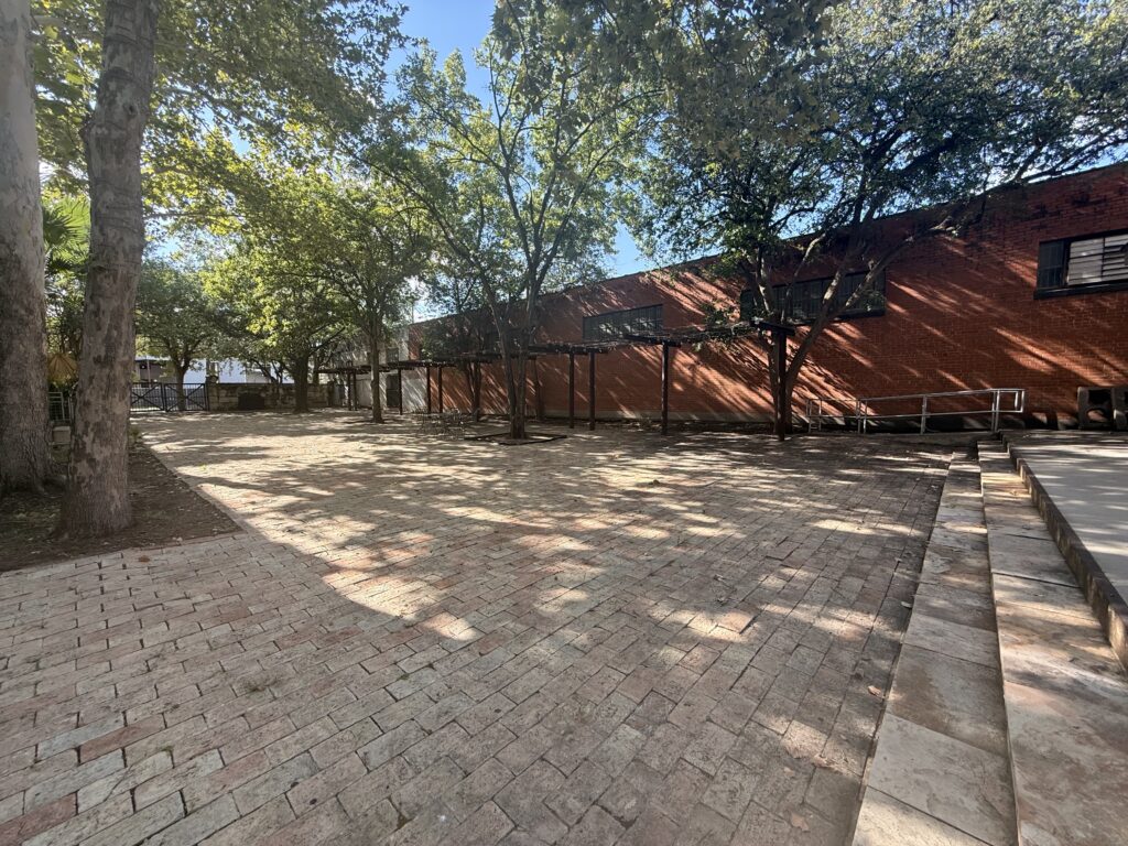 Open outdoor area with trees and brick paving for private events in San Antonio.